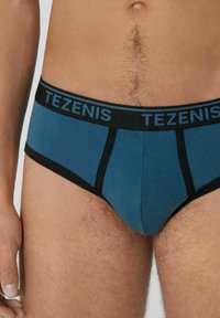 Tezenis Herrenunterwäsche in Dunkeltürkis mit schwarzen Akzenten. Sie zeichnet sich durch eine glatte Textur, einen elastischen Bund und ein körperbetontes Design aus.