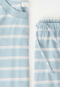 Haut en maille à manches courtes rayé bleu clair et blanc et short assorti avec cordon, posés à plat sur une surface blanche.