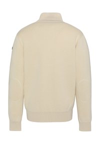 Maglione color crema con colletto alto e polsini a coste, dotato di toppe sui gomiti e un design a maglia testurizzata nella parte posteriore.