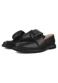 Schwarze Lederloafers mit einer übergroßen Schleifendetail auf der Vorderseite, flacher Sohle und glatter Oberfläche. Minimalistisches Design ohne zusätzliche Akzente.