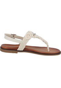Płaskie sandały w kolorze tan z plecionym, kremowym paskiem i z przodem na palce. Posiadają regulowany pasek wokół kostki oraz teksturowaną podeszwę.