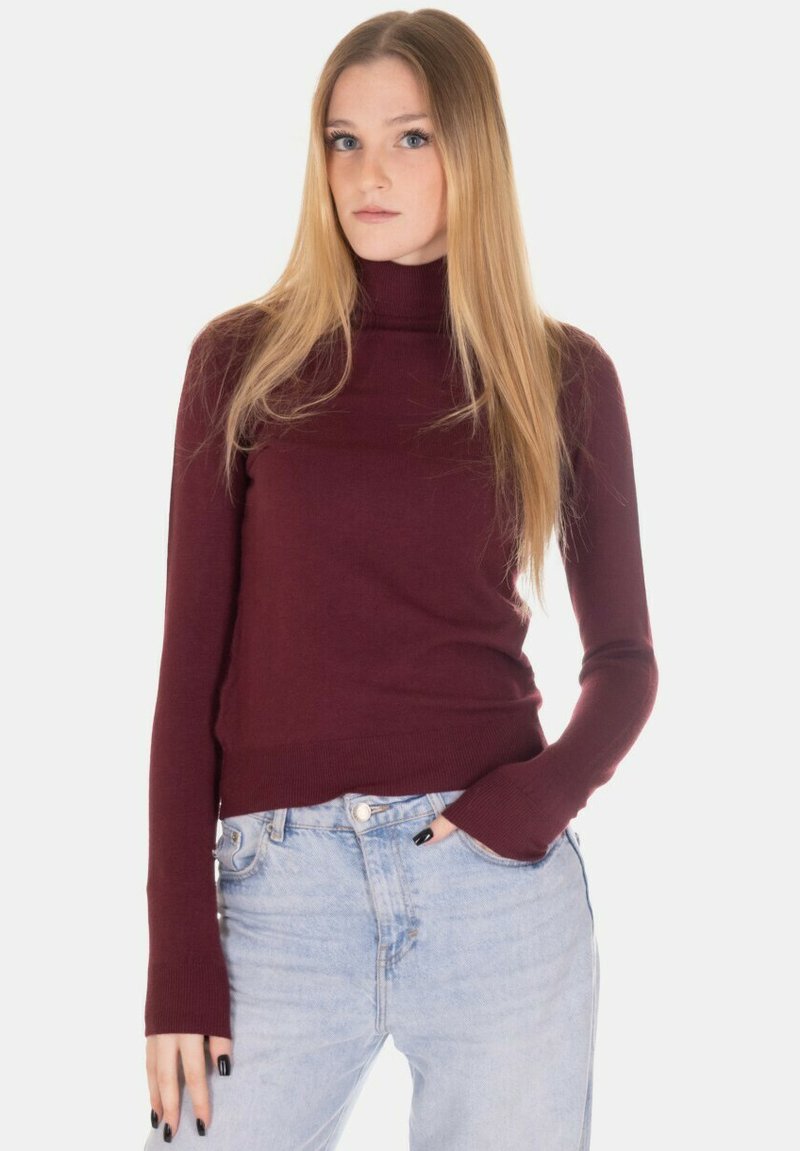 Maglione dolcevita bordeaux in materiale morbido con maniche lunghe e design aderente, abbinato a jeans a vita alta azzurri chiari.