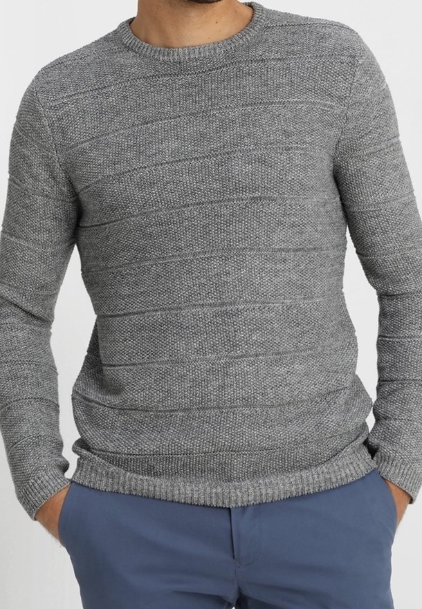 Pull en maille grise texturée avec motifs à côtes horizontales, col rond et poignets ajustés, porté avec un pantalon bleu. Finition en tissu doux.
