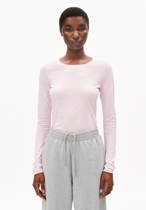 Hellrosa langärmliges Oberteil mit rundem Ausschnitt, kombiniert mit grauer Jogginghose mit elastischem Bund und Seitentaschen.