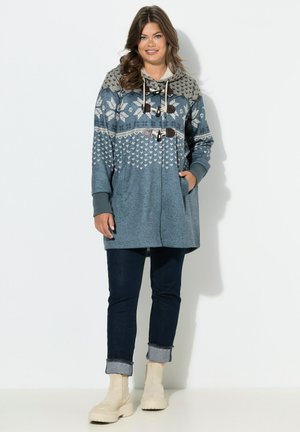 Huvtröja i blått med mönstrad design, försedd med en mjuk fleecefoder och knäppningar med toggles. Matchas med mörka jeans och ljusa ankelboots.