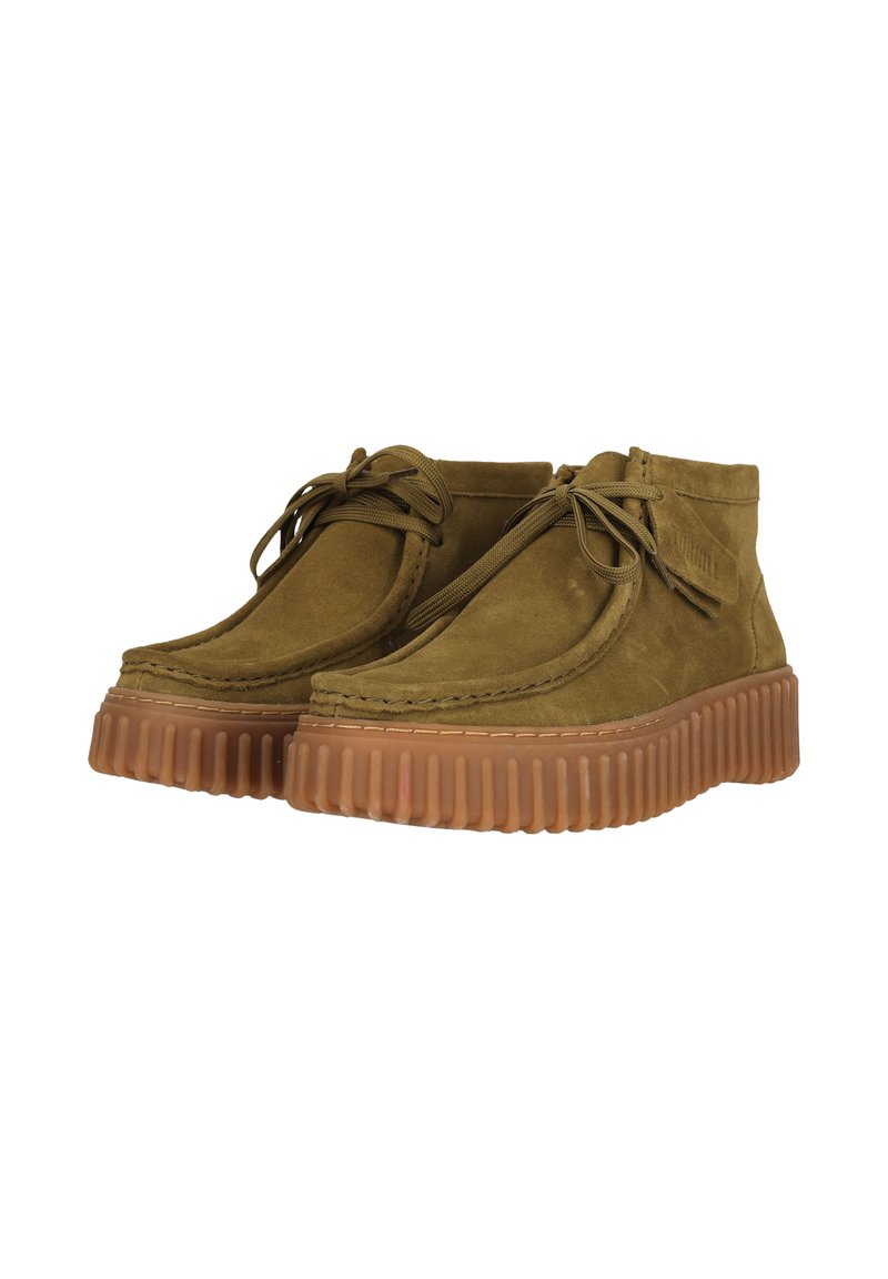 Botines de ante verde oliva con puntera redonda, diseño de cordones y una suela de goma gruesa y texturizada en color marrón.