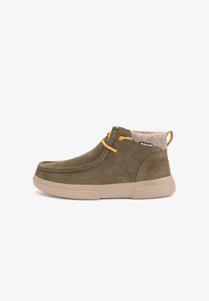 Bottines en suède vert olive avec semelle en caoutchouc beige, lacets jaunes et doublure textile grise douce. Présente des détails cousus et une boucle pour un enfilage facile.