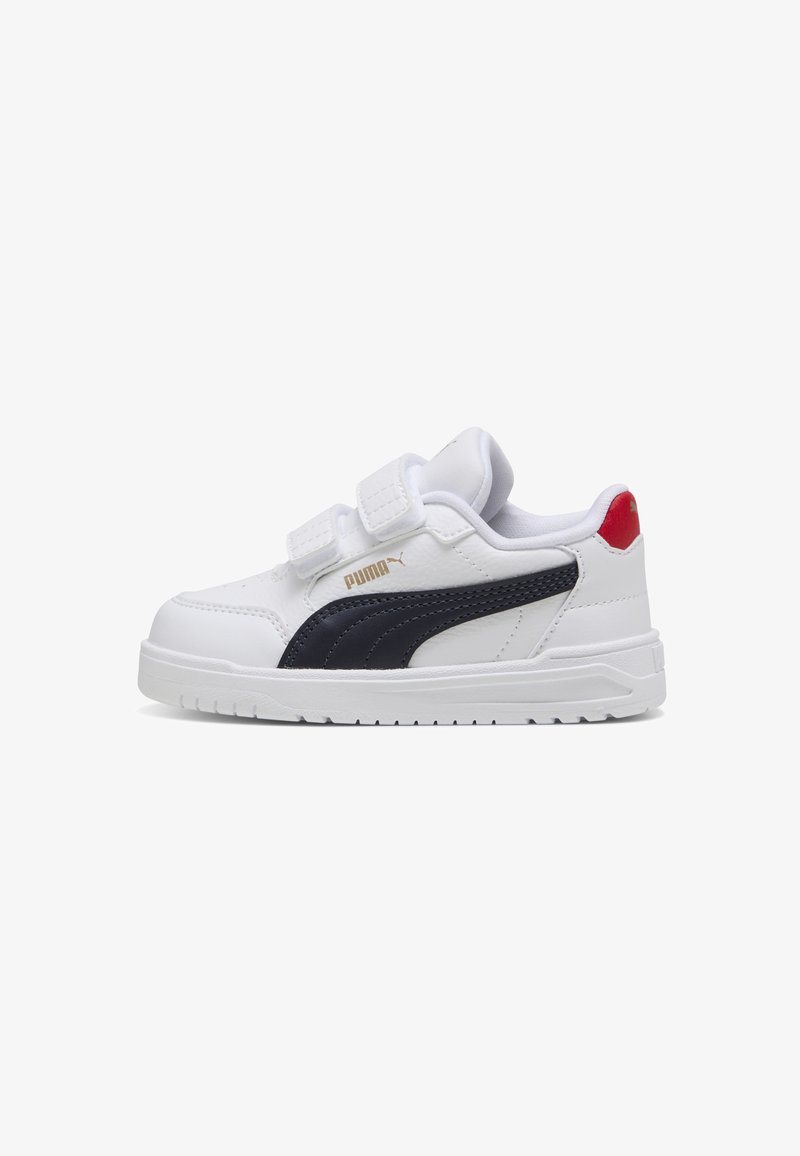 White sneaker with navy accents, featuring two Velcro straps, a padded collar, and a textured rubber sole. Gold logo on the side.