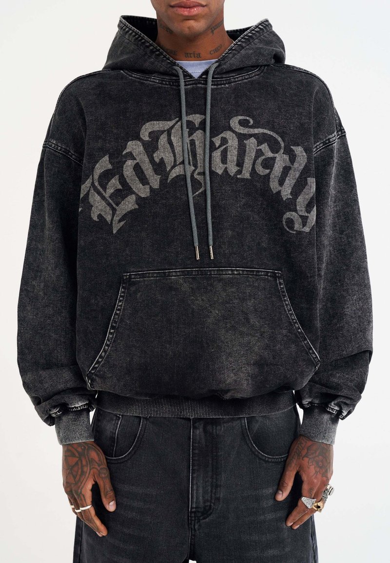 Black hooded sweatshirt in distressed denim with grey lettering. Features a front pocket and ribbed cuffs. Casual, oversized fit.