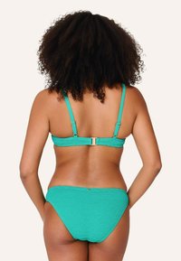 Conjunto de bikini turquesa con un acabado texturizado, tirantes ajustables y un cierre metálico en la parte posterior. Diseño simple con acentos mínimos.