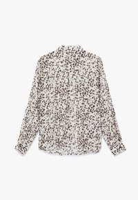 Leichte, langärmlige Bluse aus einem beigen Stoff mit einem braunen Punktmuster. Verfügt über einen klassischen Kragen und eine durchgehende Knopfleiste.