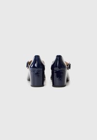 Scarpe con tacco in vernice blu navy, con punta arrotondata, cinturino alla caviglia e tacco a blocco. Texture liscia con finitura brillante e delicato dettaglio con fibbia.