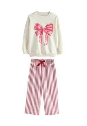 Sweatshirt mit einem großen pinken Schleifengrafik auf einem cremfarbenen Hintergrund, kombiniert mit rosa-weißen gestreiften Hosen mit elastischem Bund und Schleifenbindung.