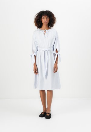 Striped cotton dress with a round neckline, tie details at the waist and sleeves, and a loose fit, paired with black, studded shoes.