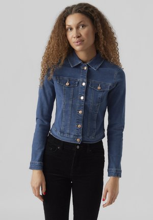 Chaqueta de mezclilla en azul oscuro con una cintura ajustada, dos bolsillos en el pecho y botones metálicos. Mangas largas con un cuello clásico.