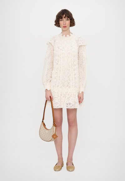 Pitkähuivi mekko off-white-värissä, jossa on puffiolkapäät, röyhelöhelma ja kukkakuvio. Mukana vaalea kuvioitu käsilaukku ja kultaiset ballerinat.
