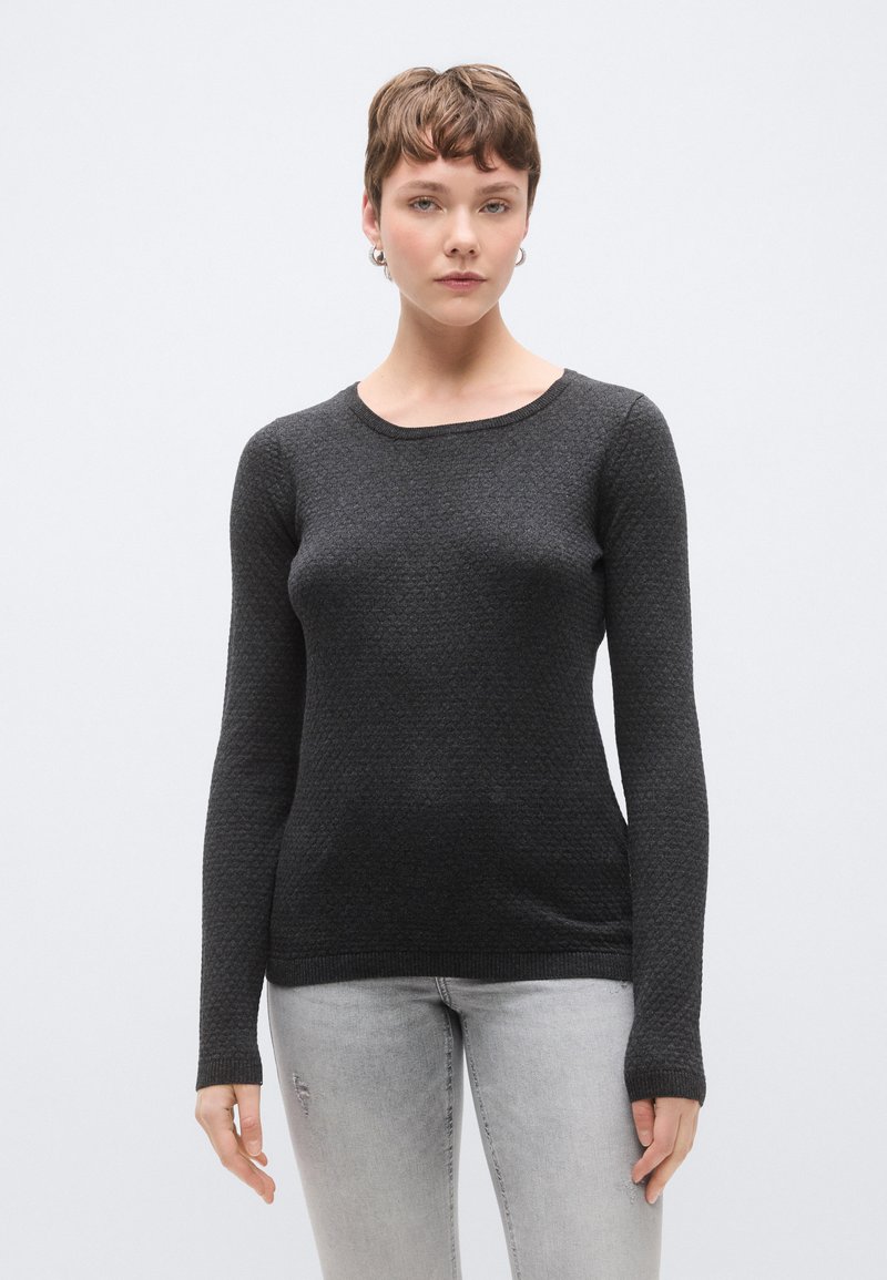 Μαύρο πουλόβερ με μακριά μανίκια, υφασμάτινη υφή, στρογγυλή λαιμόκοψη και εφαρμοστή γραμμή. Συνδυάζεται με ανοιχτό γκρι τζιν με φθορές.