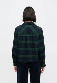 Καρό πουκάμισο σε πράσινο και ναυτικό μπλε με κουμπιά, γιακά, μακριά μανίκια και άνετη εφαρμογή. Υφασμένο ύφασμα με υφή και τσέπες στο πίσω μέρος.