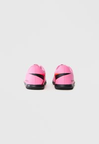 Egy pár rózsaszín Nike Mercurial teremfoci cipő fekete swoosh logókkal, hátulról nézve, fehér háttér előtt.