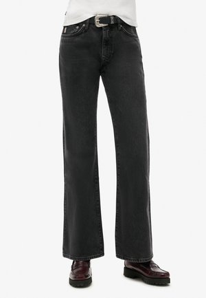Jean noir droit associé à des mocassins bordeaux et une ceinture noire avec une boucle argentée.