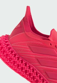 Scarpa sportiva rosa con parte superiore traspirante in tessuto testurizzato e una suola distintiva a motivo a reticolo, progettata per le prestazioni.