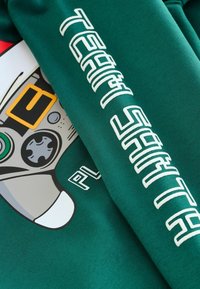 Green sweatshirt featuring a graphic design of a game controller. The left sleeve has "TEAM SANTA" printed in white text.