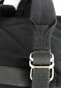 Schwarzes Stoffband mit strukturiertem Finish, ausgestattet mit Metalldetails zur Einstellung und einem glatten Lederakzent. Nahaufnahme zeigt die Detailverarbeitung der Nähte.