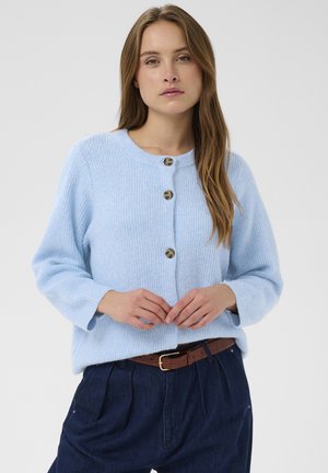 Light blue ribbed cardigan with round neckline and three buttons. Long sleeves, soft texture, paired with navy trousers and brown belt.