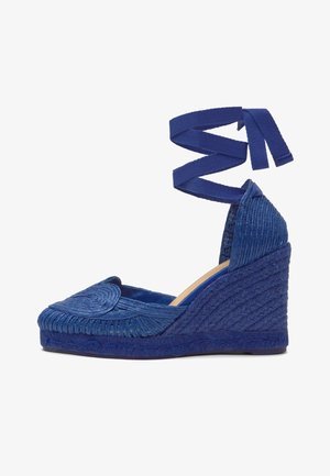 Alpargata cuña azul tejida con lazo para atar en el tobillo y detalle de puntera redonda, con entresuela trenzada texturizada y talón cerrado.