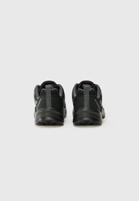 Schwarze Sportschuhe mit einem strukturierten Obermaterial aus Stoff, Gummisohle und verstärktem Absatz. Verfügt über Ziehlöcher für einfaches Anziehen und Branding an den Seiten.