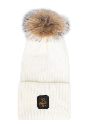 Bonnet en tricot blanc avec une texture côtelée, doté d'un pompon en fausse fourrure marron duveteux et d'une étiquette de marque noire sur l'ourlet replié.