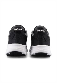 Ett par svarta sportskor med vita sulor, sedd bakifrån, med nätmaterial och märkesfästen på hälarna.