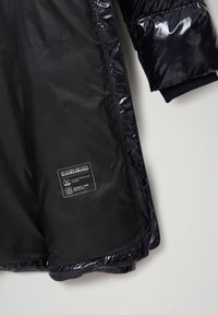 Chaqueta acolchada azul marino con acabado brillante, que cuenta con puños acanalados, un forro interior repelente al agua y una etiqueta con información sobre el cuidado del tejido.