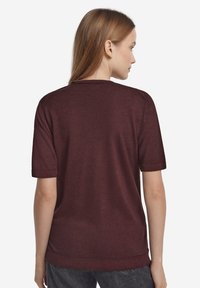 Vinröd kortärmad tröja med rund halsringning, med en slät textur och ribbad nederkant, designad för en avslappnad passform.