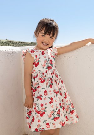 Abito floreale con uno sfondo bianco, decorato con ciliegie rosse e fiori rosa, maniche corti a volant e gonna a campana.