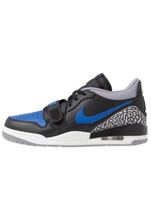 Sneaker nera bassa con punta e swoosh blu, collo imbottito grigio, dettagli a stampa elefante sul tallone, suola intermedia bianca e unità di ammortizzazione ad aria.