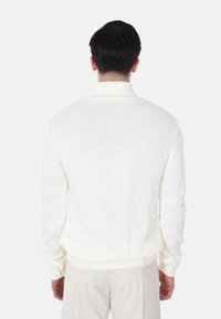 Maglione bianco a maglia con collo alto, polsini e orlo a coste, caratterizzato da un motivo testurizzato e una vestibilità morbida.