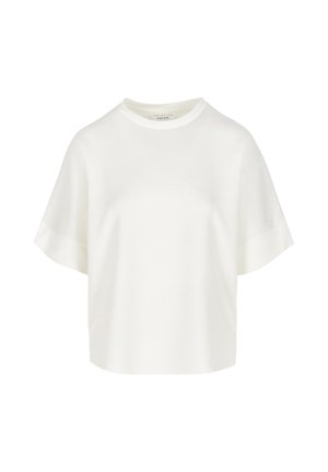 Maglietta bianca oversize a maniche corte con collo rotondo e polsini delle maniche risvoltati, esposta su uno sfondo uniforme.