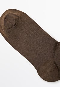 Brun strikket sok lagt fladt, som viser en fin ribbet tekstur samt forstærkede tå- og hælområder på en hvid baggrund.