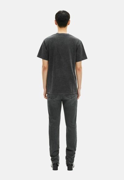 Tamsiai pilkas medvilnės marškinėliai su trumpomis rankovėmis ir klasikinio stiliaus, derinami su atitinkančiais pilkais džinsais ir juodais aukštakulniais batais.