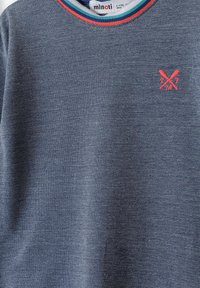 Šedý pletený sveter s textúrovaným povrchom, s kruhovým výstrihom a červenými a teal pruhmi, a malým ružovým prekročeným logom netopiera.