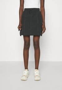 Gonna nera con fascia elastica in vita, tasche laterali e cuciture bianche. Progettata con un taglio dritto e un'estetica casual e funzionale.