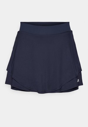 Falda deportiva azul marino con un diseño en capas, hecha de una tela suave y elástica. Presenta una cinturilla ancha y un detalle de logo en el dobladillo.