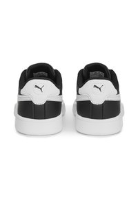 Une paire de baskets Puma noir et blanc vue de l'arrière, présentant un logo Puma noir sur la languette blanche et des semelles intermédiaires blanches.