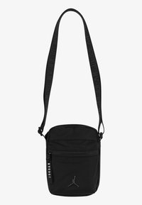 Svart multifunktionell axelremsväska i tyg; har ett huvudfack med dragkedja, justerbar rem och logotypdetaljer.