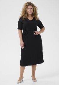 Black dress made of soft fabric with a V-neck, short sleeves, and a drawstring waist. Features a straight cut and side slits.
