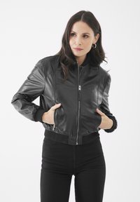 Giacca bomber in pelle nera con zip frontale, polsini e orlo a costine. Presenta tasche laterali e una texture liscia.