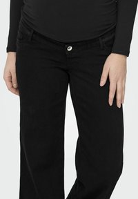 Črne jeans hlače iz jeansa s ravnimi hlačnicami, s srebrnim gumbom za zapiranje in sprednjimi žepi. Tkanina ima gladko teksturo in enotno barvo.