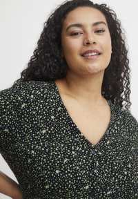 Rochie neagră cu imprimeu floral verde și alb, având decolteu în V, mâneci scurte și detalii cu nasturi în față. Textură de țesătură netedă.