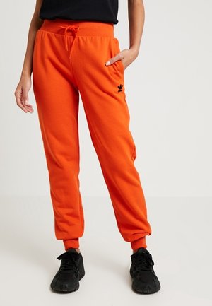 Orange Sweatpants mit einem elastischen Bund, Kordelzug und seitlichen Taschen. Mit einem schwarzen Logo am Oberschenkel und schmal zulaufenden Bündchen.